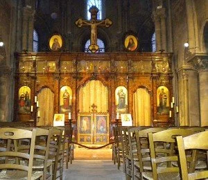 Interior of small Catholic Church with wooden chairs and a golden altar.