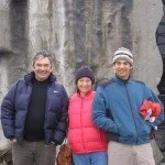 Amanda, Nathan, and Shane in winter clothing stand in front of a stone wall, smiling.