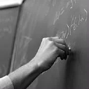 A woman’s hand writing on a blackboard.