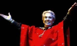 Chapels Vargas wearing a red cape, jubilant, with arms spread wide.