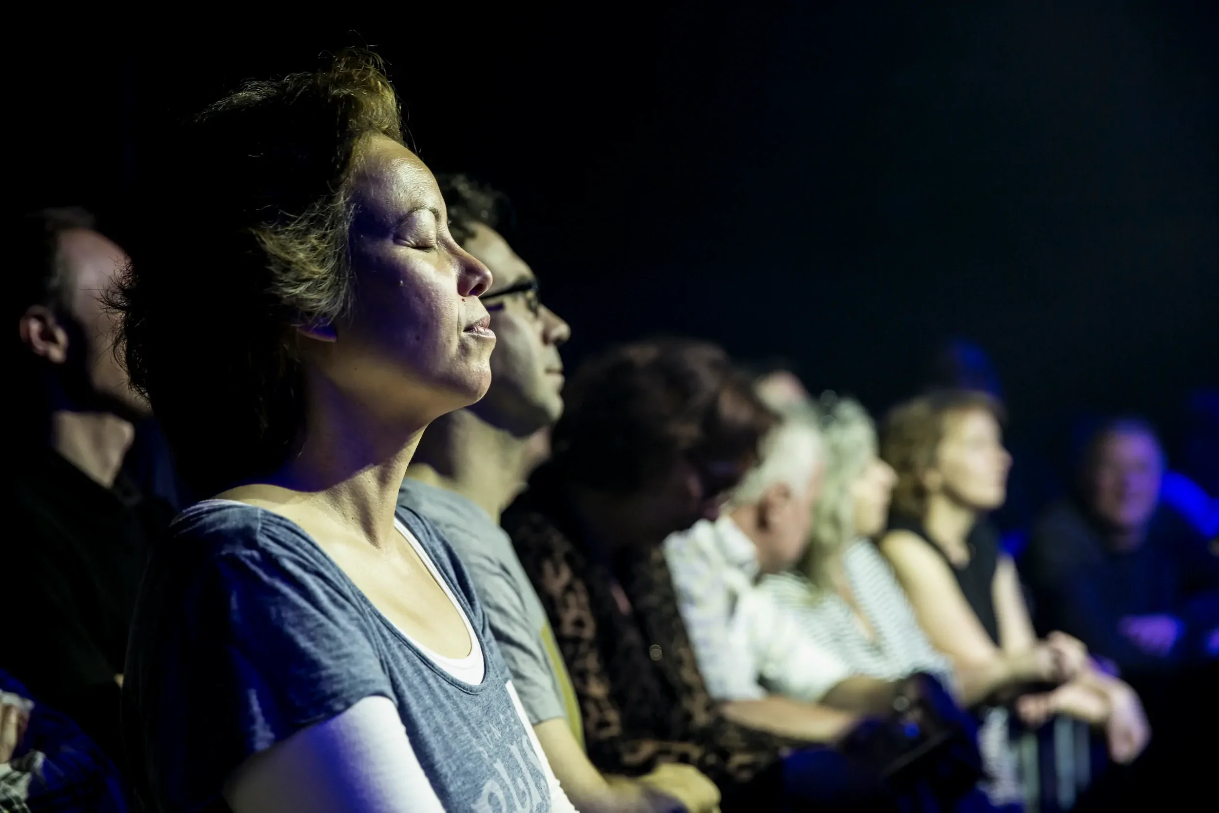 A large audience listening with their eyes closed.