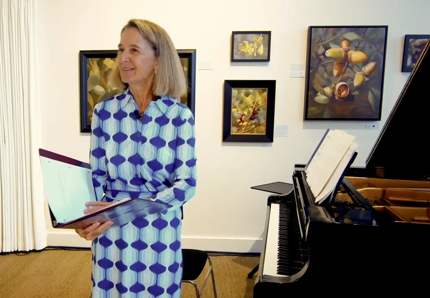 Maryliz Smith speaking to an audience alongside a grand piano.
