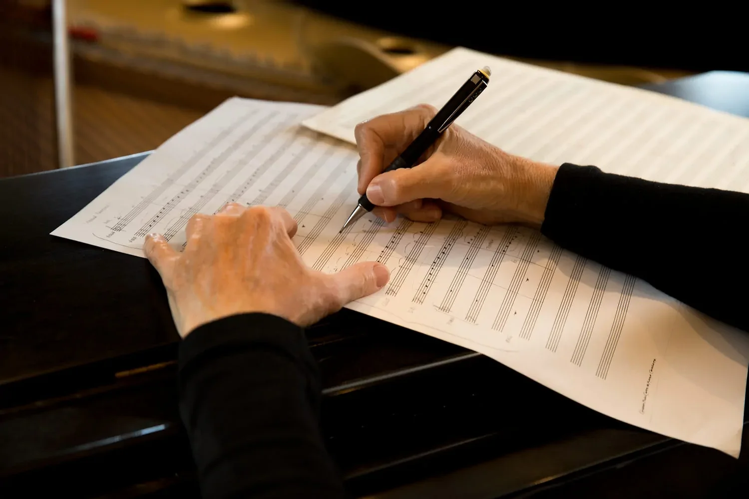 Maryliz Smith's hands writing musical notation on the edge of a grand piano