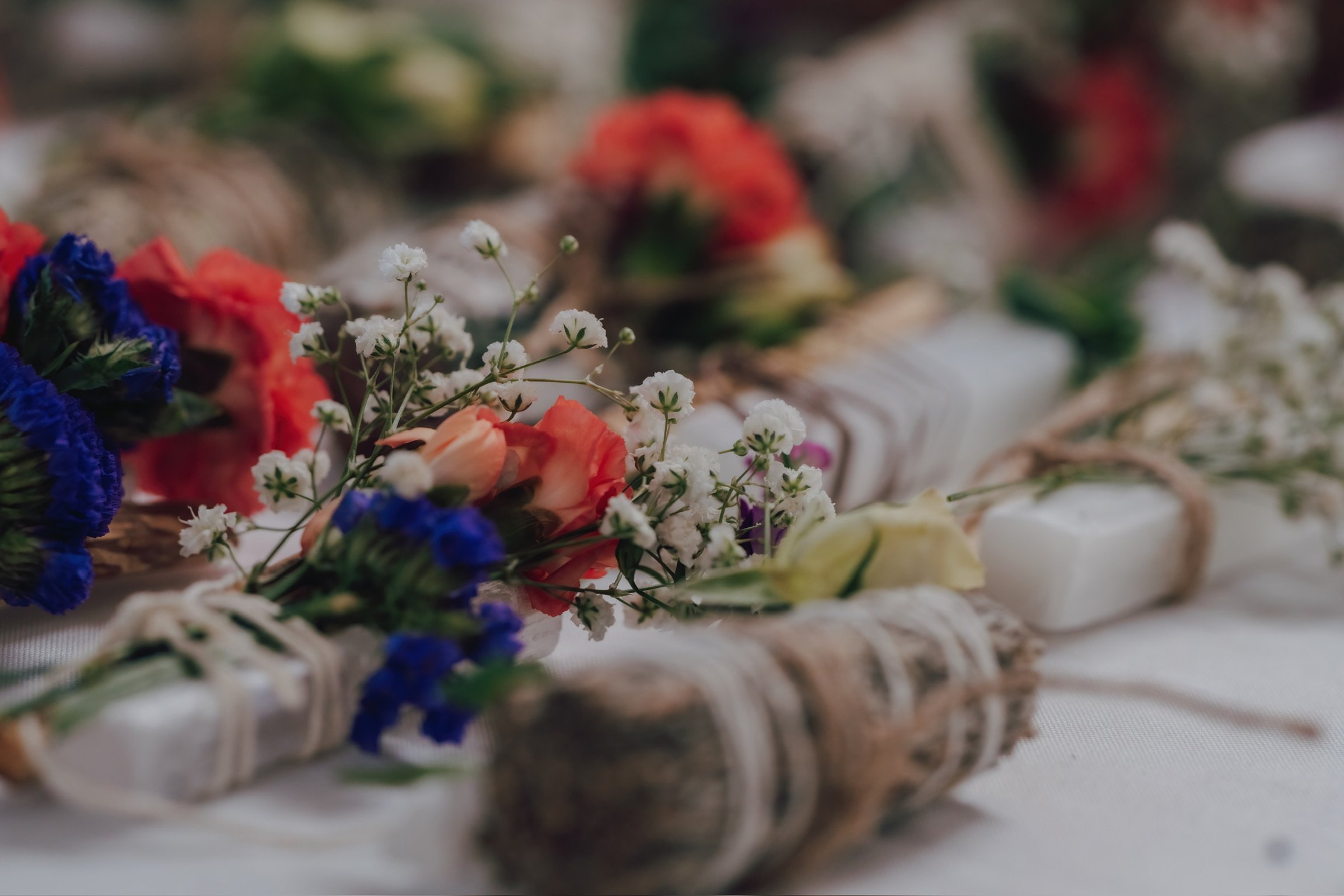 Close-up of a floral arrangement with white, orange, red, blue, and purple flowers, arranged on a table.