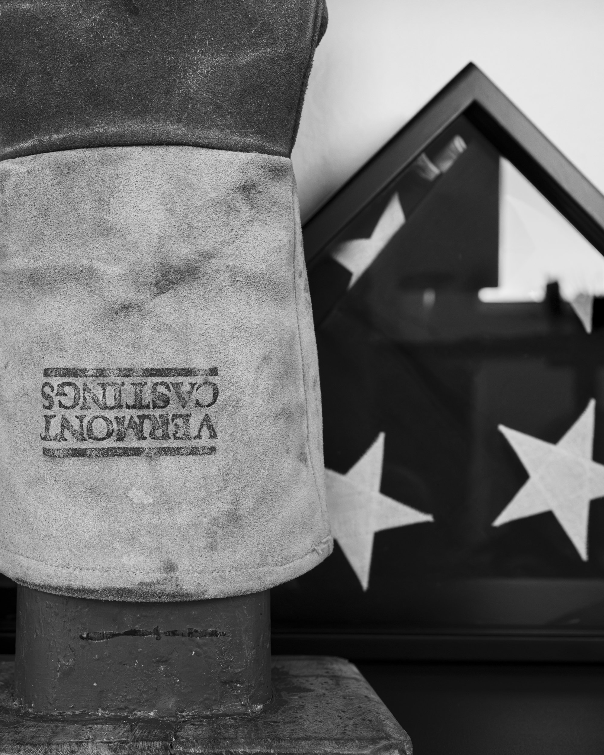 Close-up of a textured, cylindrical object, possibly a candle or sculpture, with a partial label that reads 'VETEMENTS CANDLES.' In the background, there is a black frame or mirror reflecting a star-patterned surface.