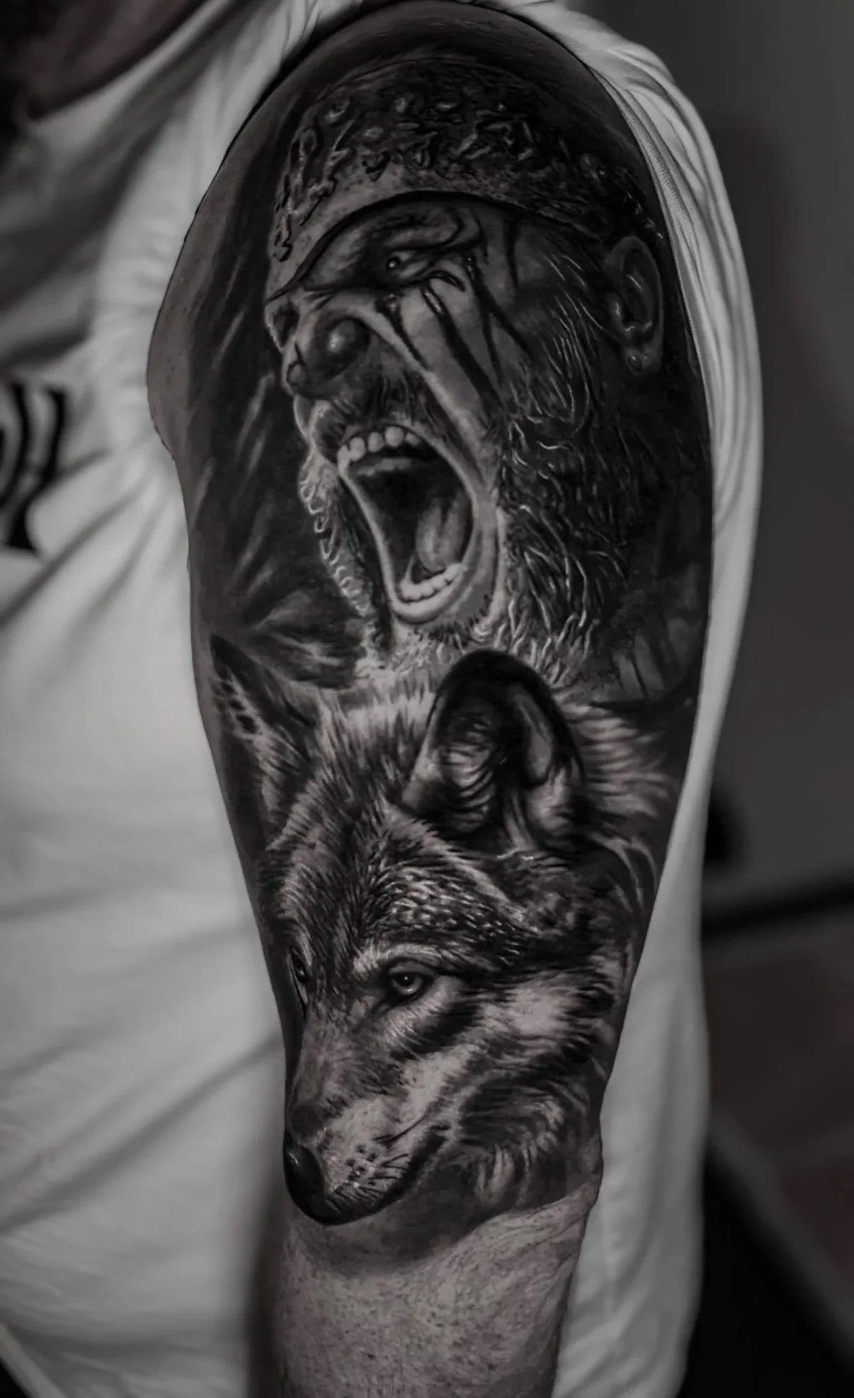 Black and gray tattoo sleeve featuring a roaring viking with long hair and beard, and a detailed wolf's face.