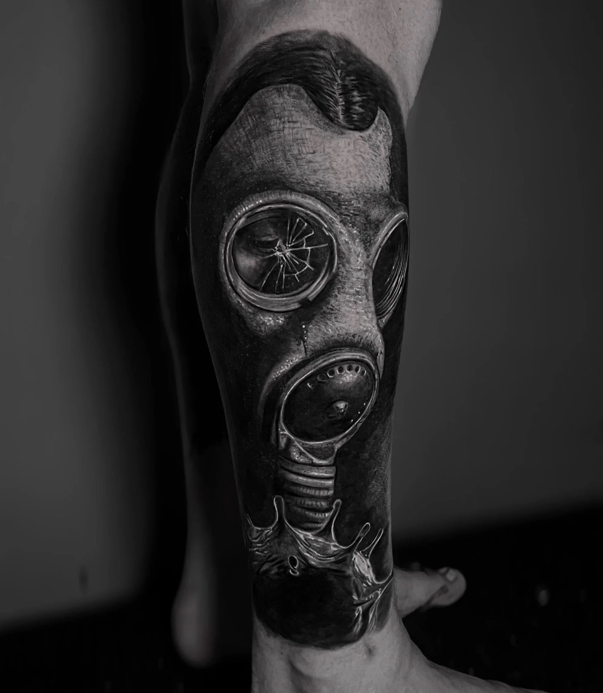 Close-up of a detailed black and grey gas mask against a dark background.