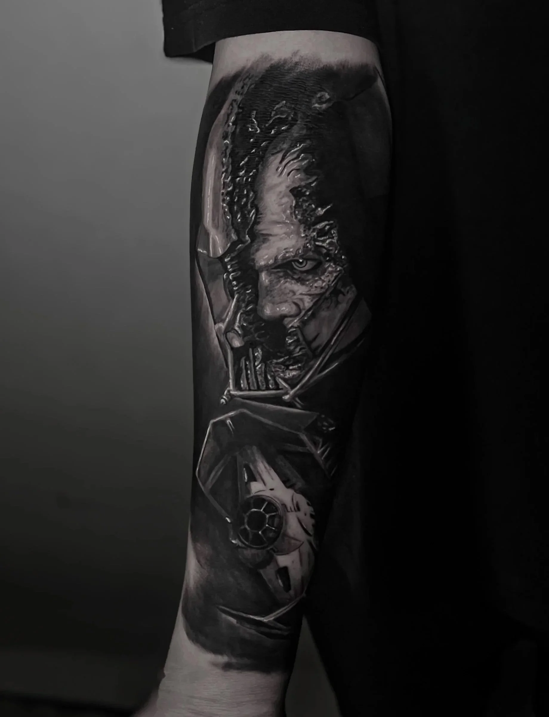 Tattoo on a person's arm featuring a detailed black and white illustration of Darth Vader