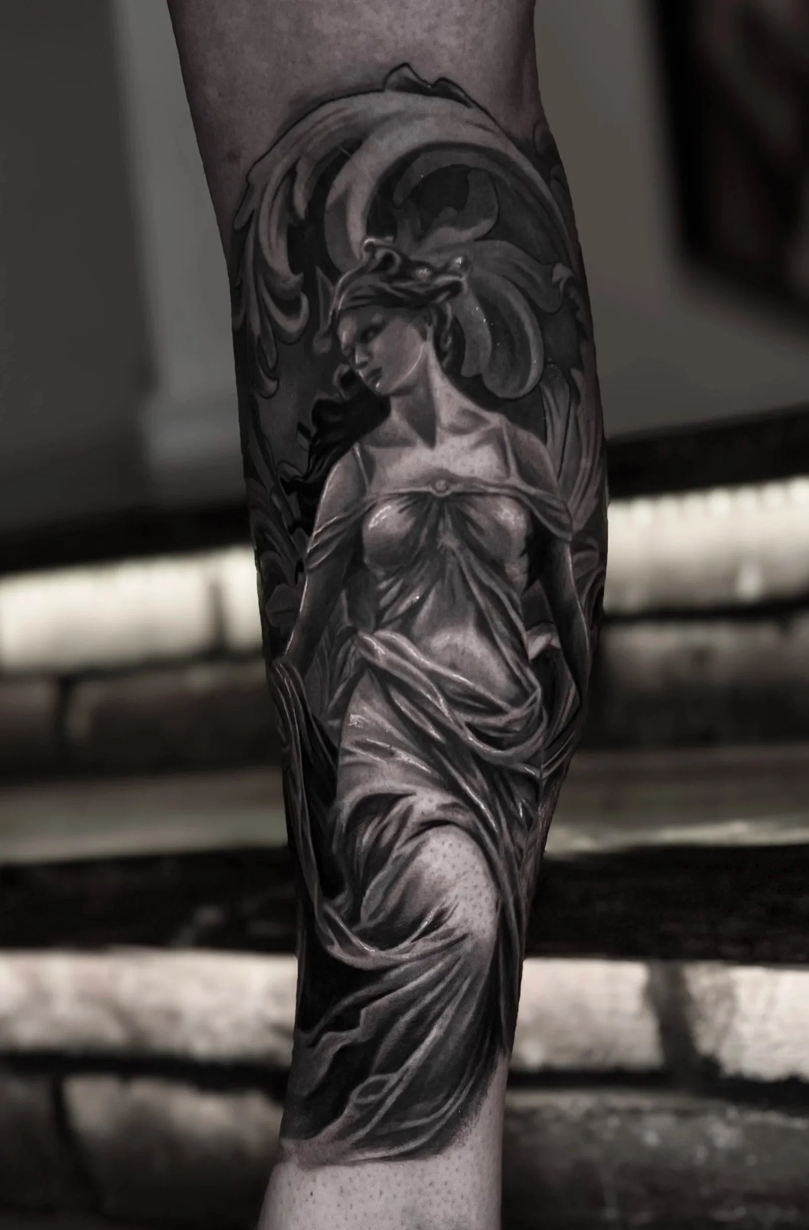 Close-up of a detailed black and grey tattoo of a sculpture of Aphrodite