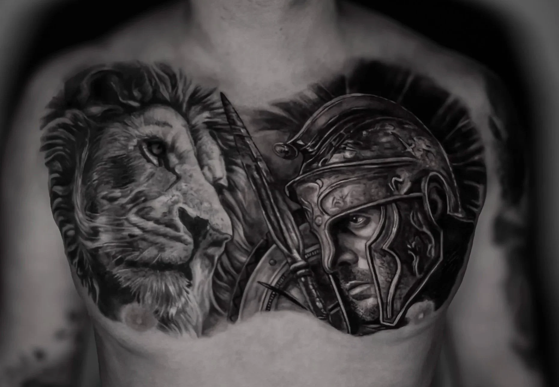 Tattoo of a lion's face and spartan warrior on a person's chest, with detailed shading and realism.