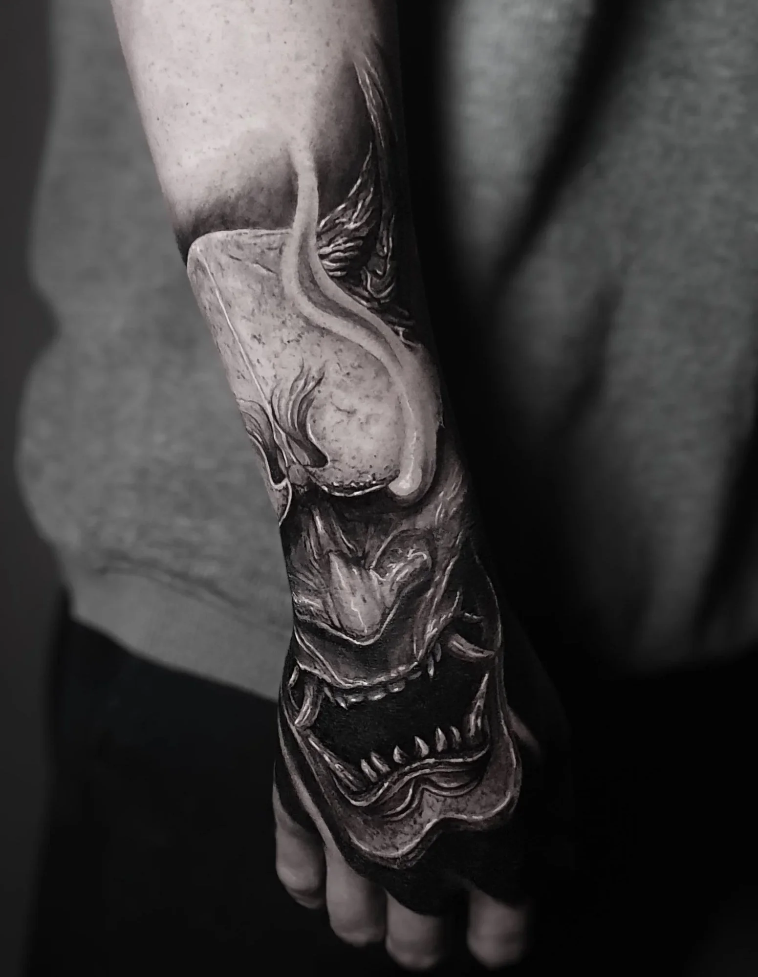 A close-up of a detailed, black and white tattoo on a person's arm, featuring a Japanese oni.