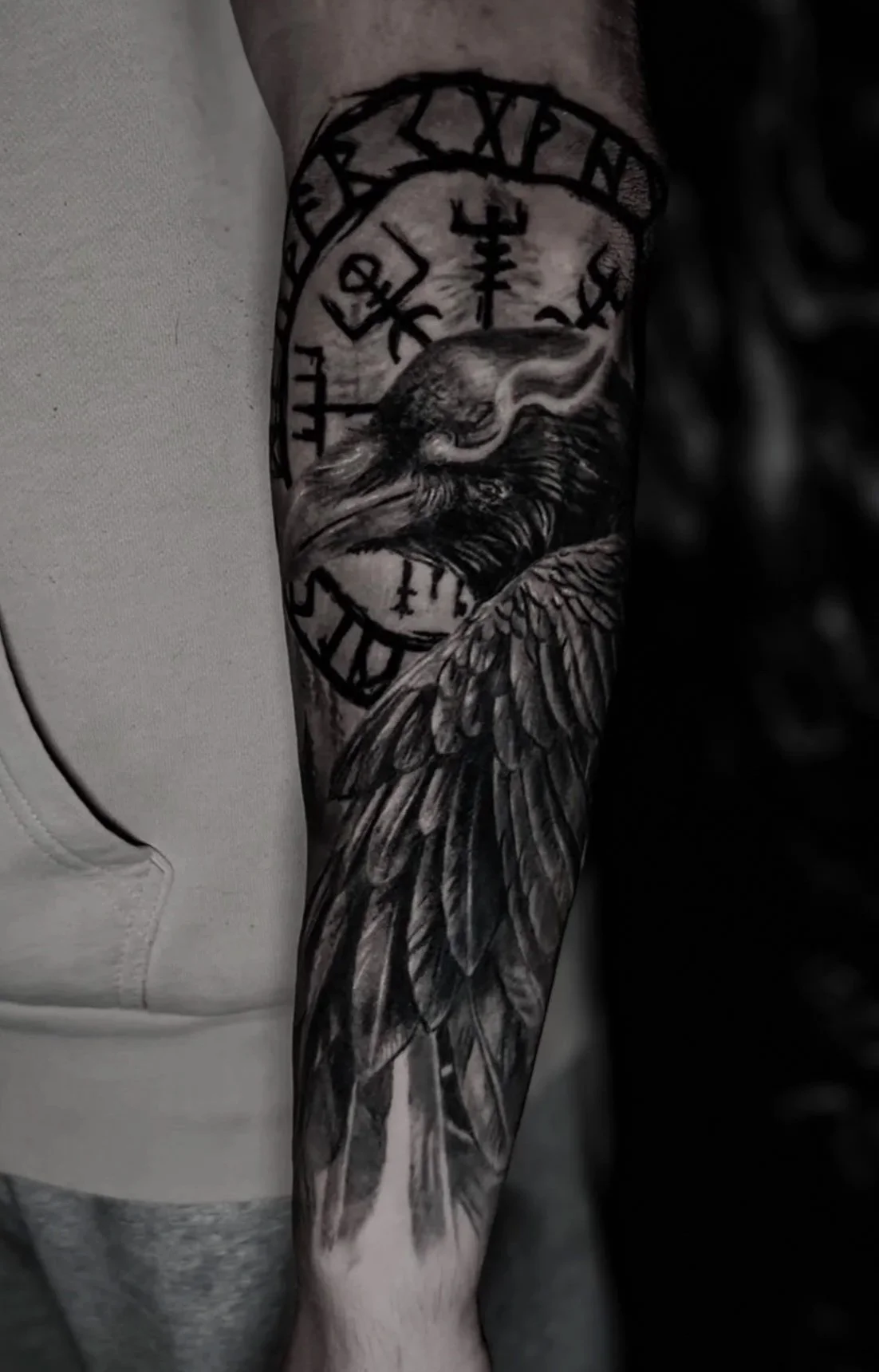 Black and gray tattoo of a bird's head with detailed feathers on a person's arm.