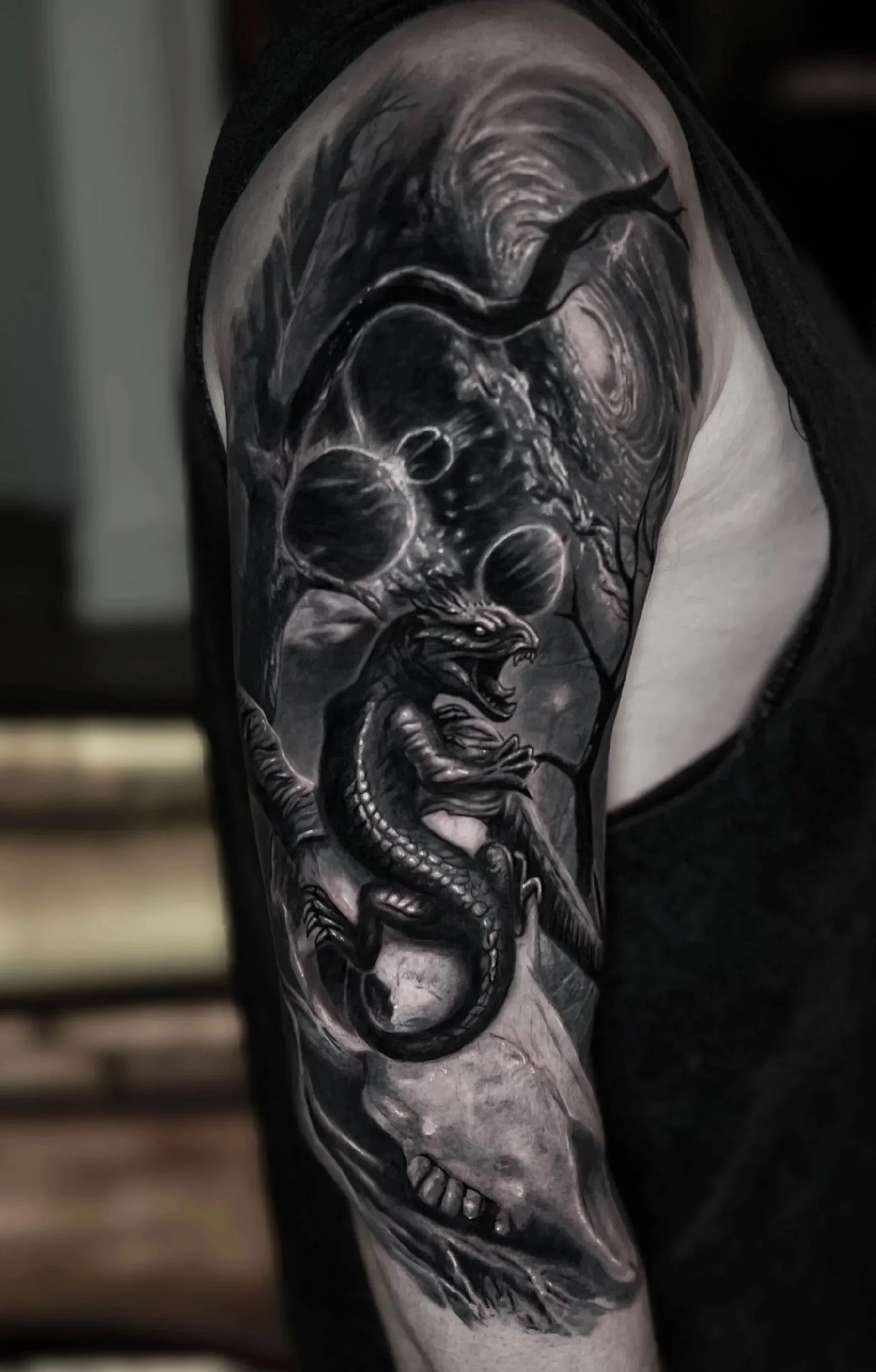 Black and grey tattoo of a lizard and galaxy on a person's arm.