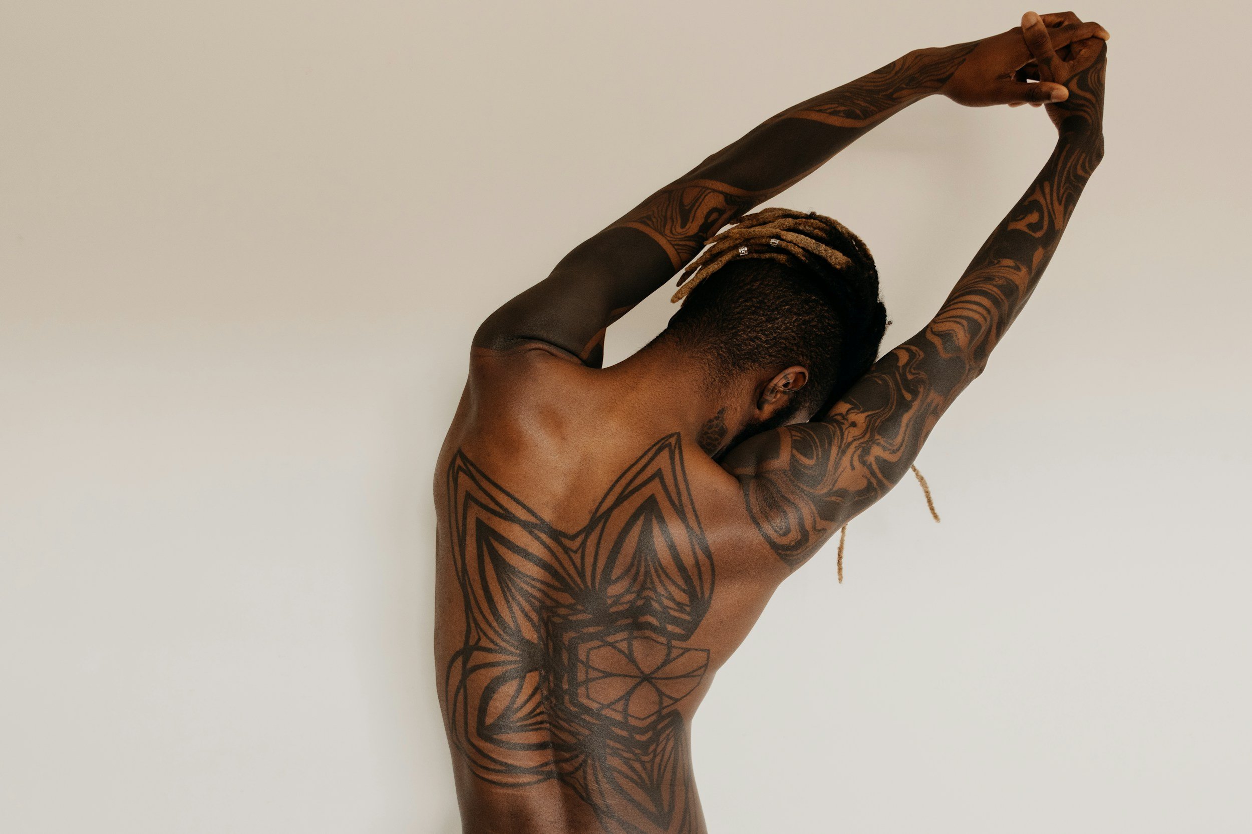 A person stretching with arms raised above their head, feeling relief from massage.