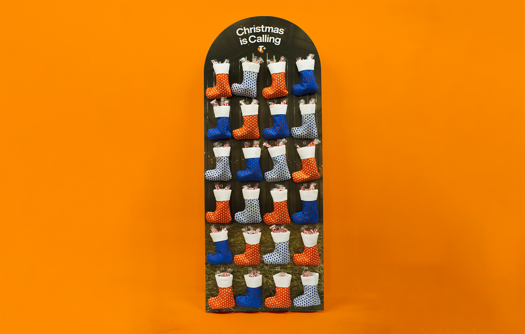 Display of Christmas stockings in red, blue, white, and black with various patterns on a black background, top reads 'Christmas is Calling'.