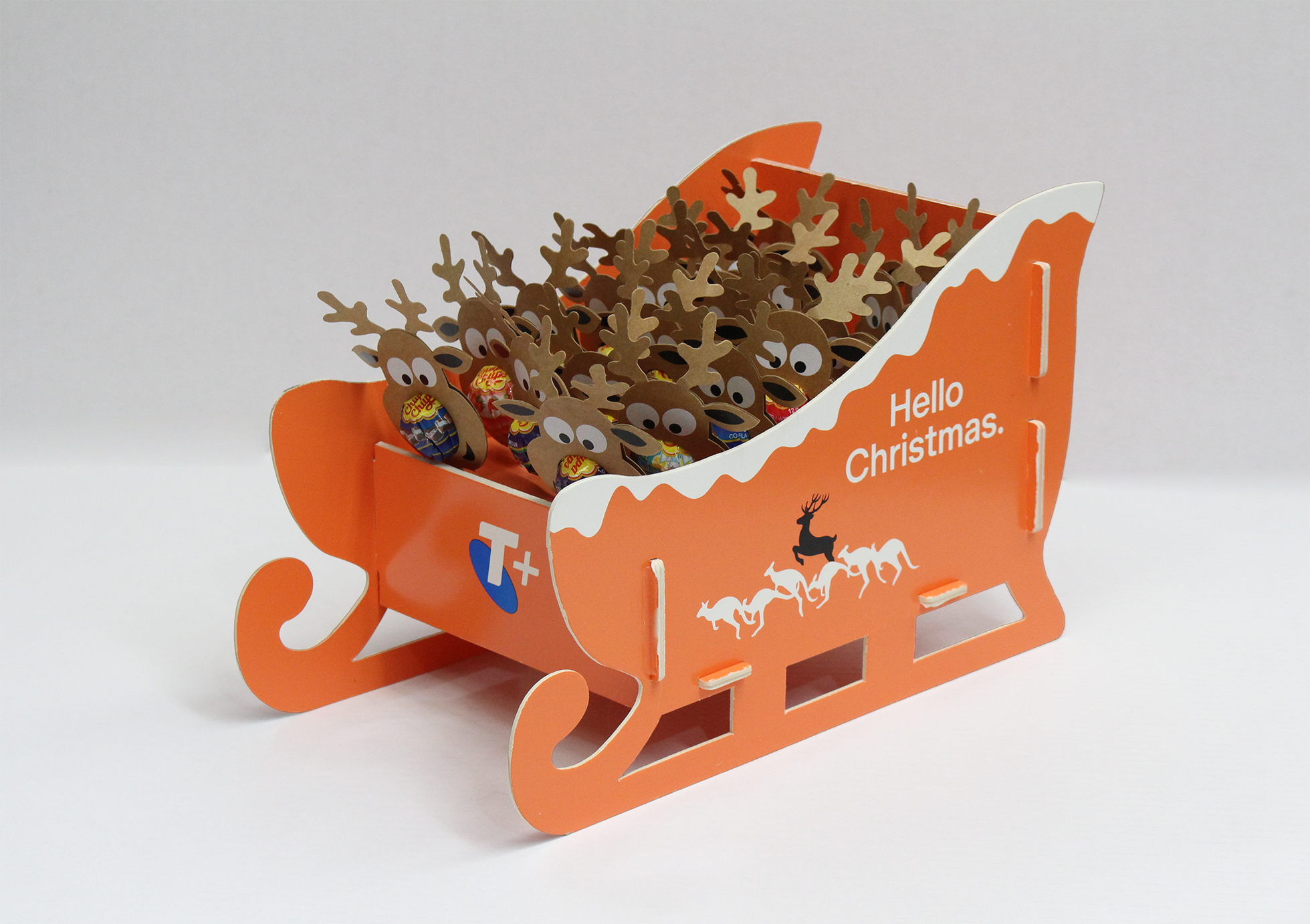 Orange sleigh-shaped box filled with chocolate reindeer and candy, decorated for Christmas with the text "Hello Christmas" and a silhouette of reindeer and snow.