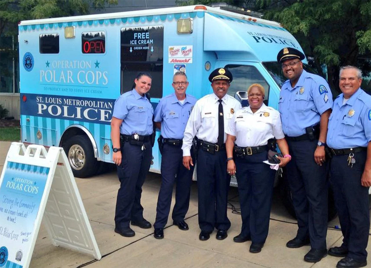 Group of seven police officers standing in front of an ice cream truck labeled Operation Polar Cops in St. Louis.
