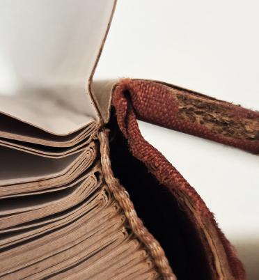 Close-up of an old, worn book with tattered cover and yellowed pages.