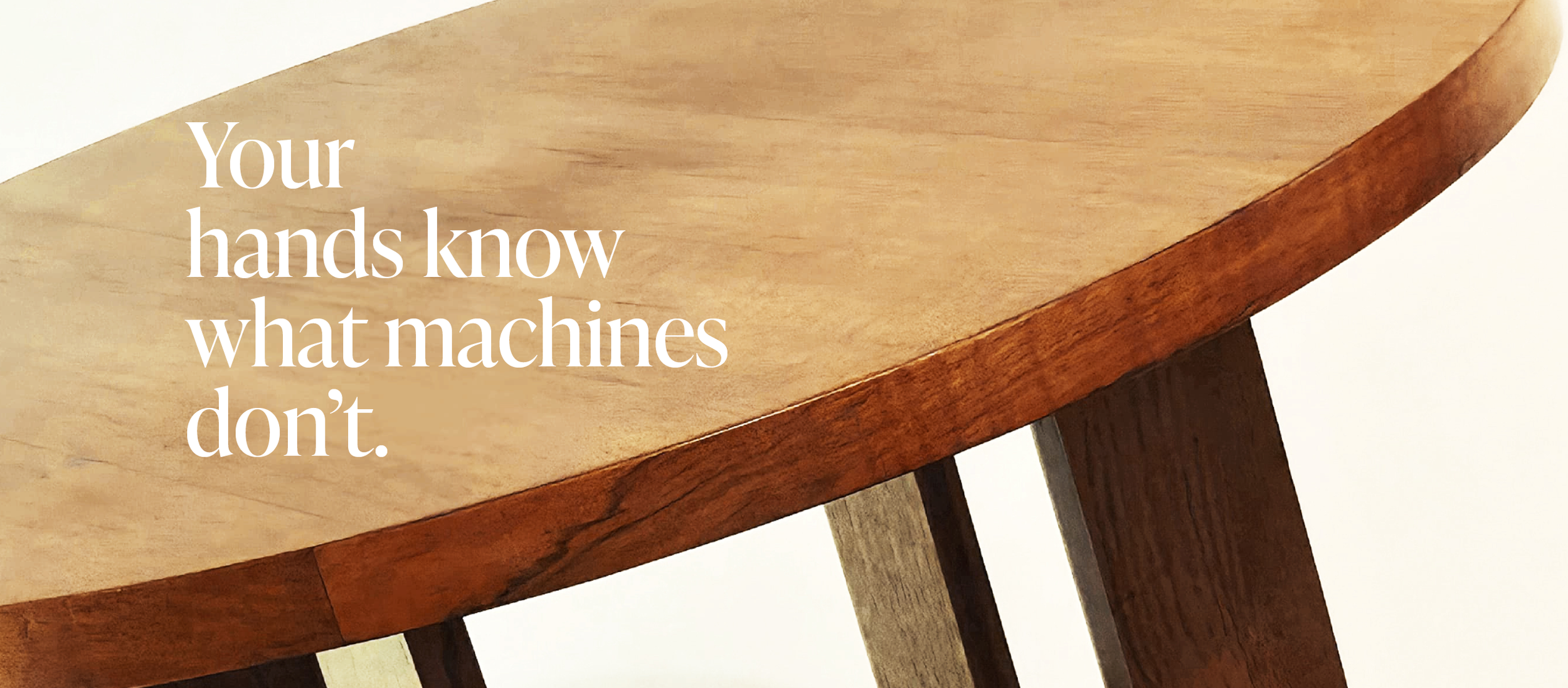 Close-up of a wooden table with a natural wood finish and a quote that reads 'Your hands know what machines don't.'