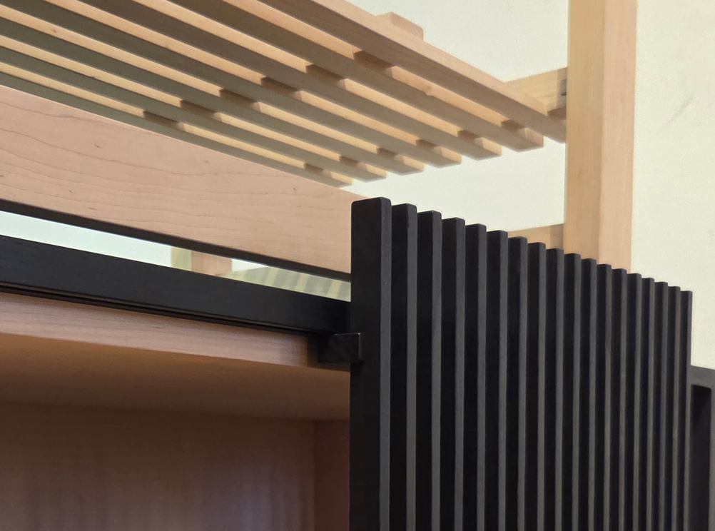 Close-up of a furniture piece with a black slatted wooden panel and light wooden shelves.