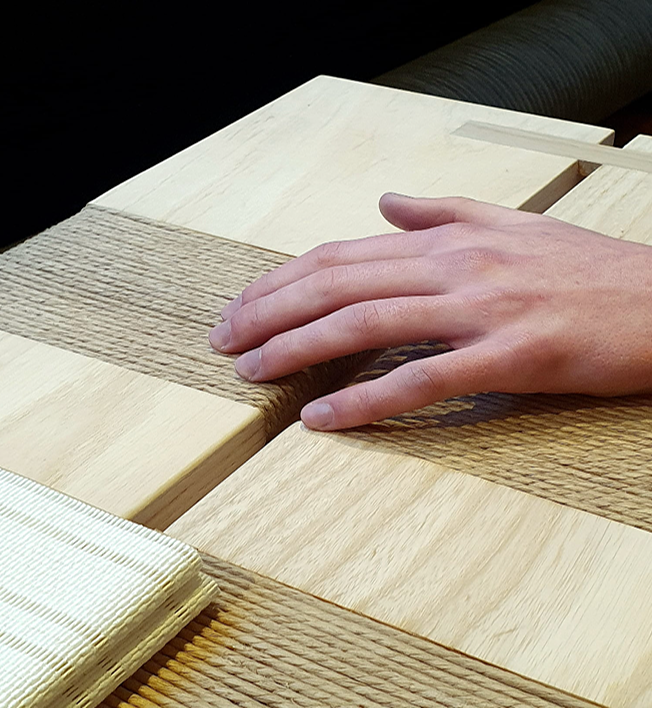 A person's hand resting on a wooden table made of alternating light and dark wood planks.