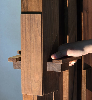 Person adjusting wooden slatted structure outdoors