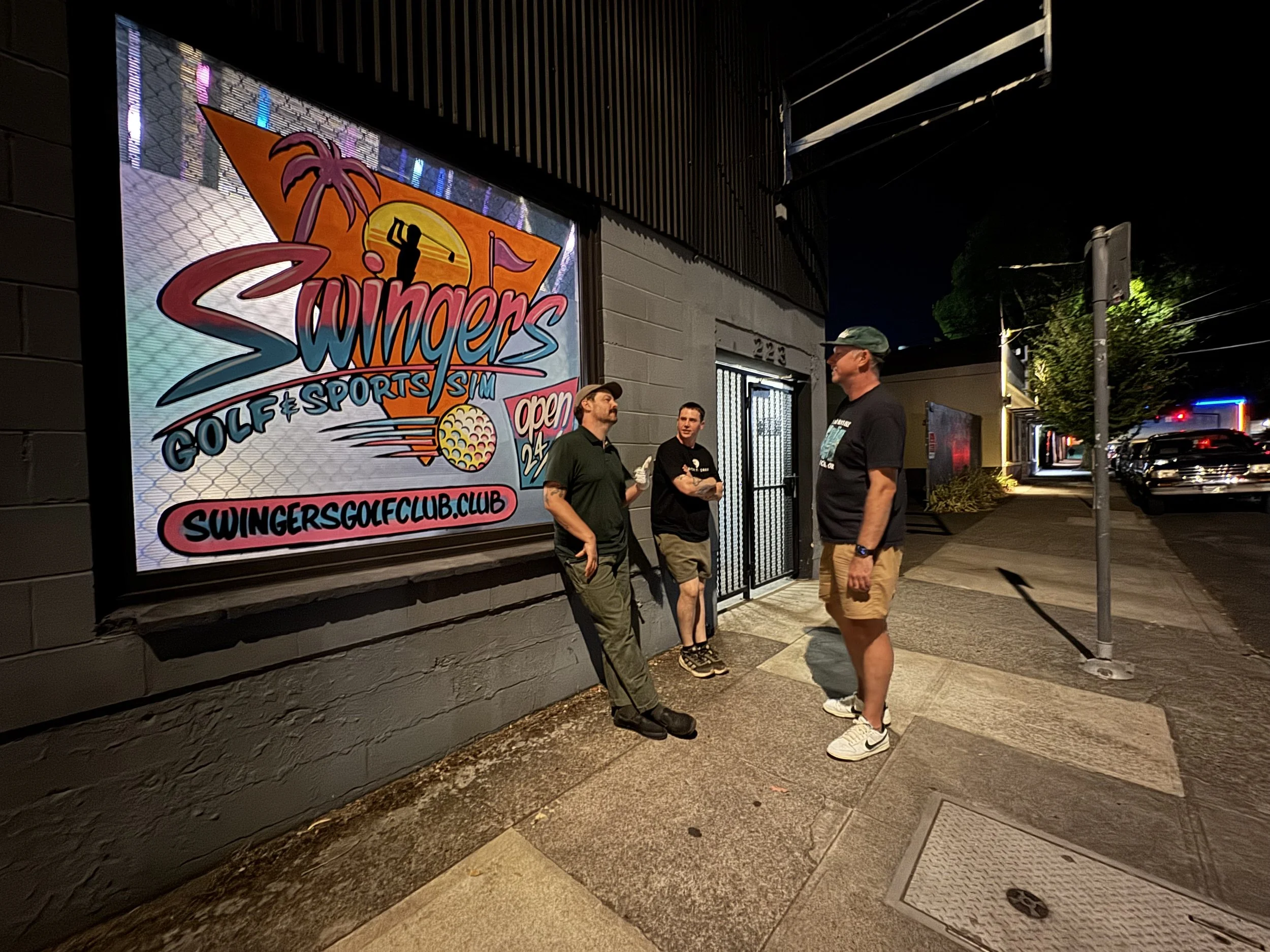 Friends stand outside Swingers Golf Club in Portland next to the colorful exterior Swingers mural.