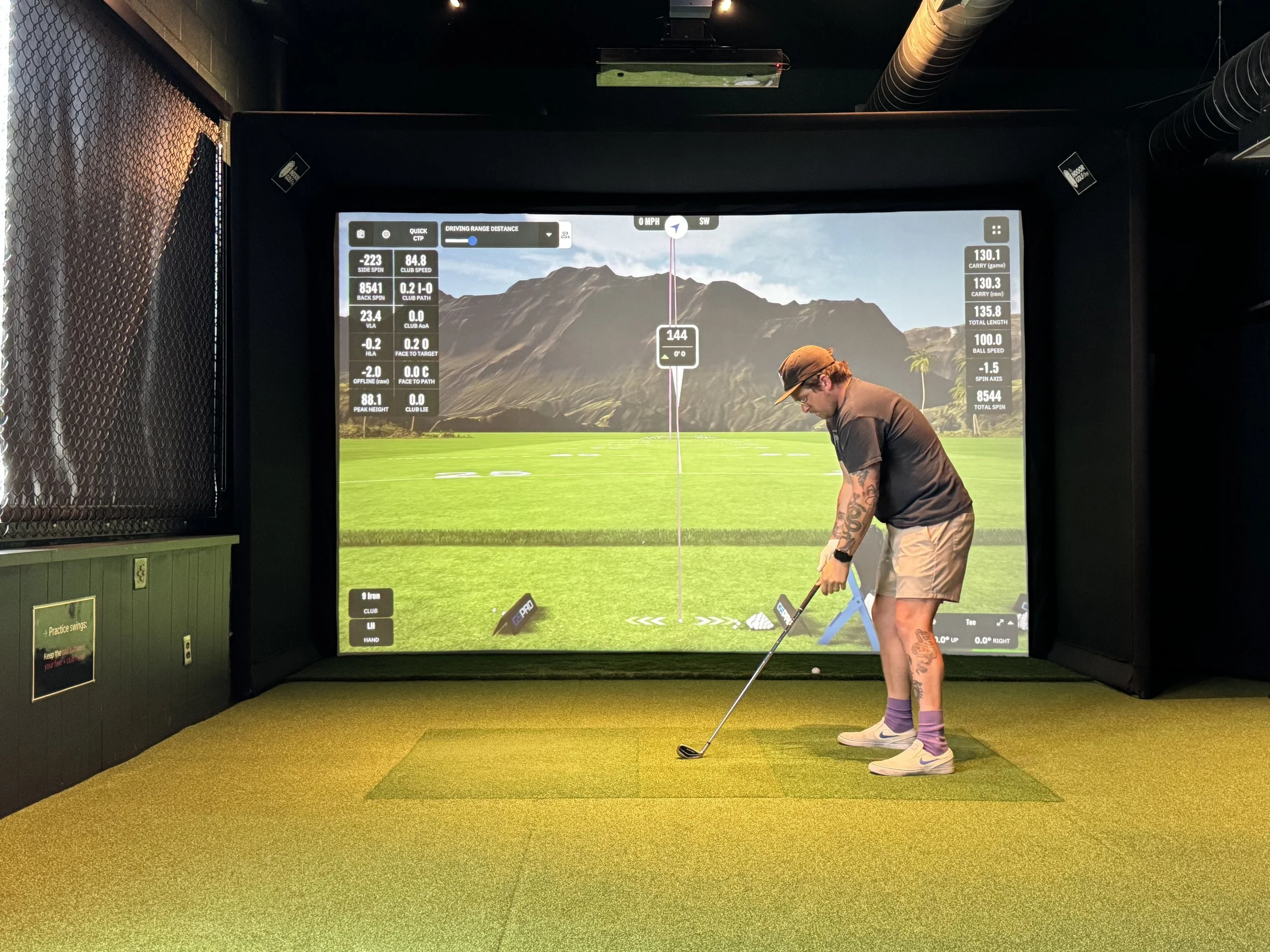 A golfer addresses the ball inside the Swingers Golf Club simulator bay in Portland, Oregon, with a Uneekor Eye XO launch monitor mounted overhead.