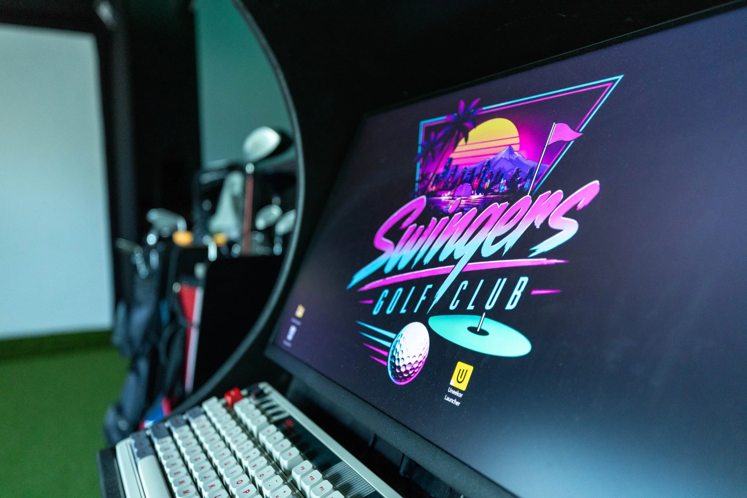 A computer monitor displaying a retro-style Miami-themed graphic for a golf club event called Summer Golf Club, with neon colors, a sunset, mountains, and golf-related icons like a golf ball and flag.