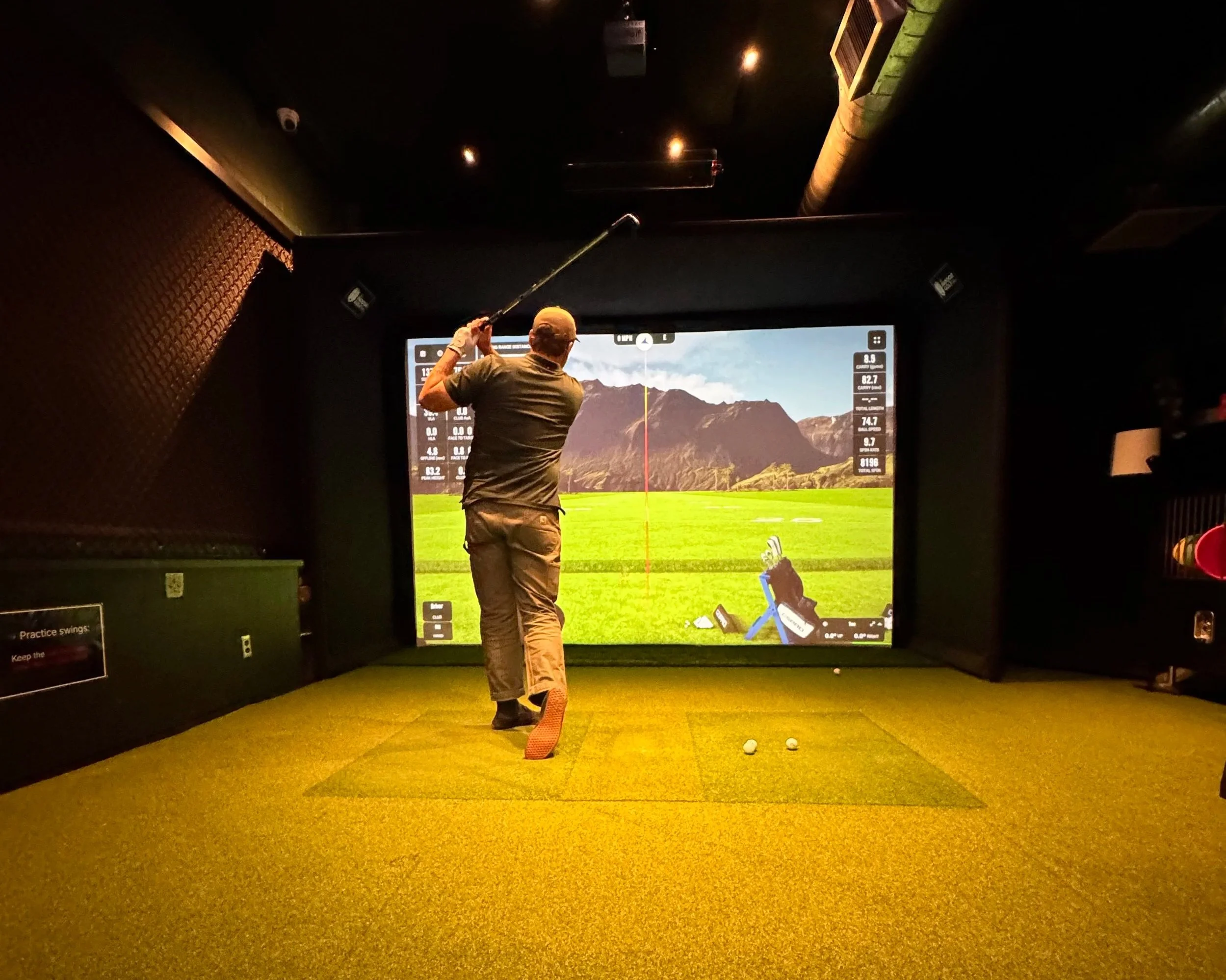 A golfer practices alone inside the private simulator bay at Swingers Golf Club in Portland.