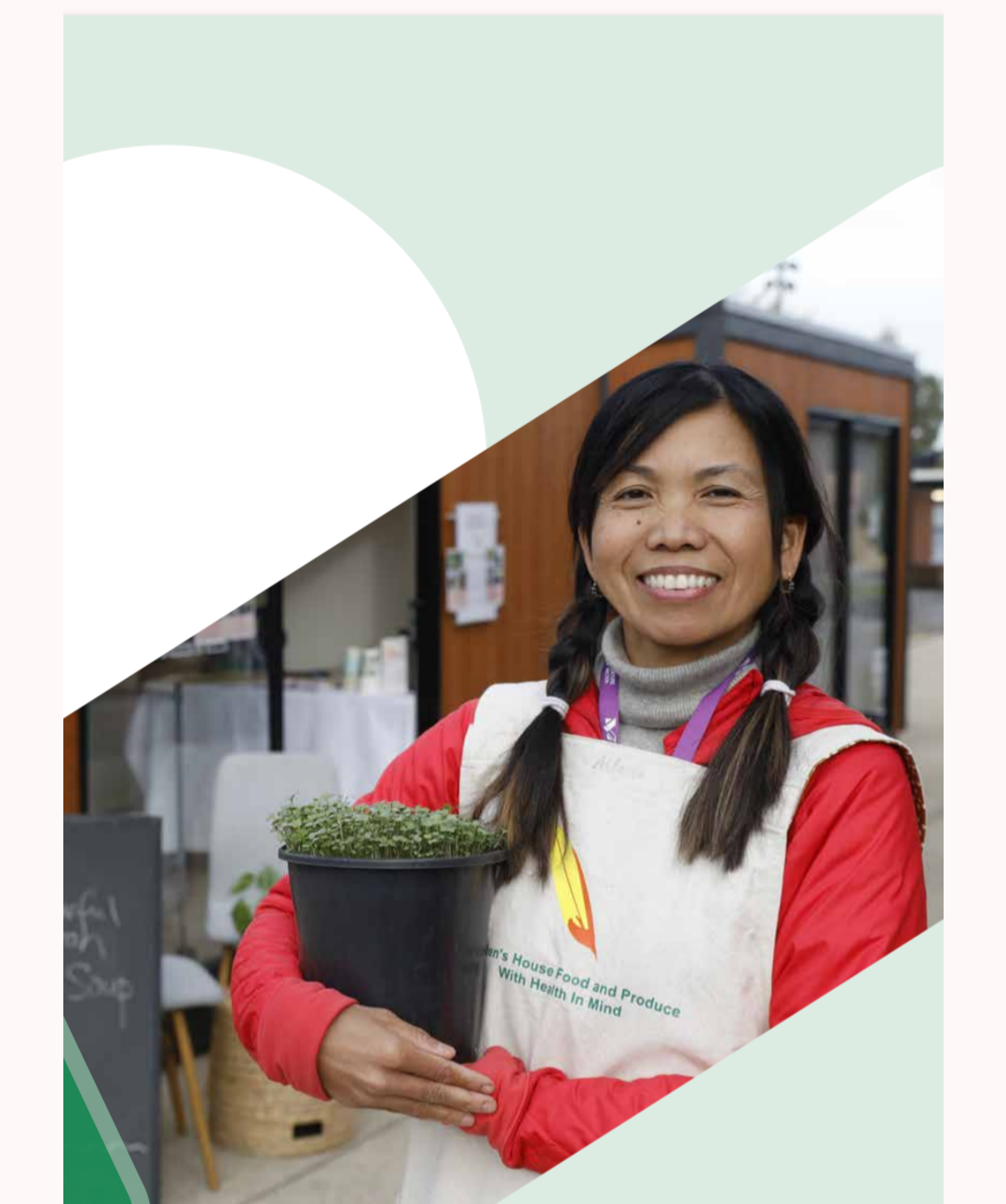 Smiling woman holding a potted plant at an outdoor market or farm stand, wearing a white apron and a red jacket.
Hot House Project for Hayden's House Food and Produce. Arlene Tribo