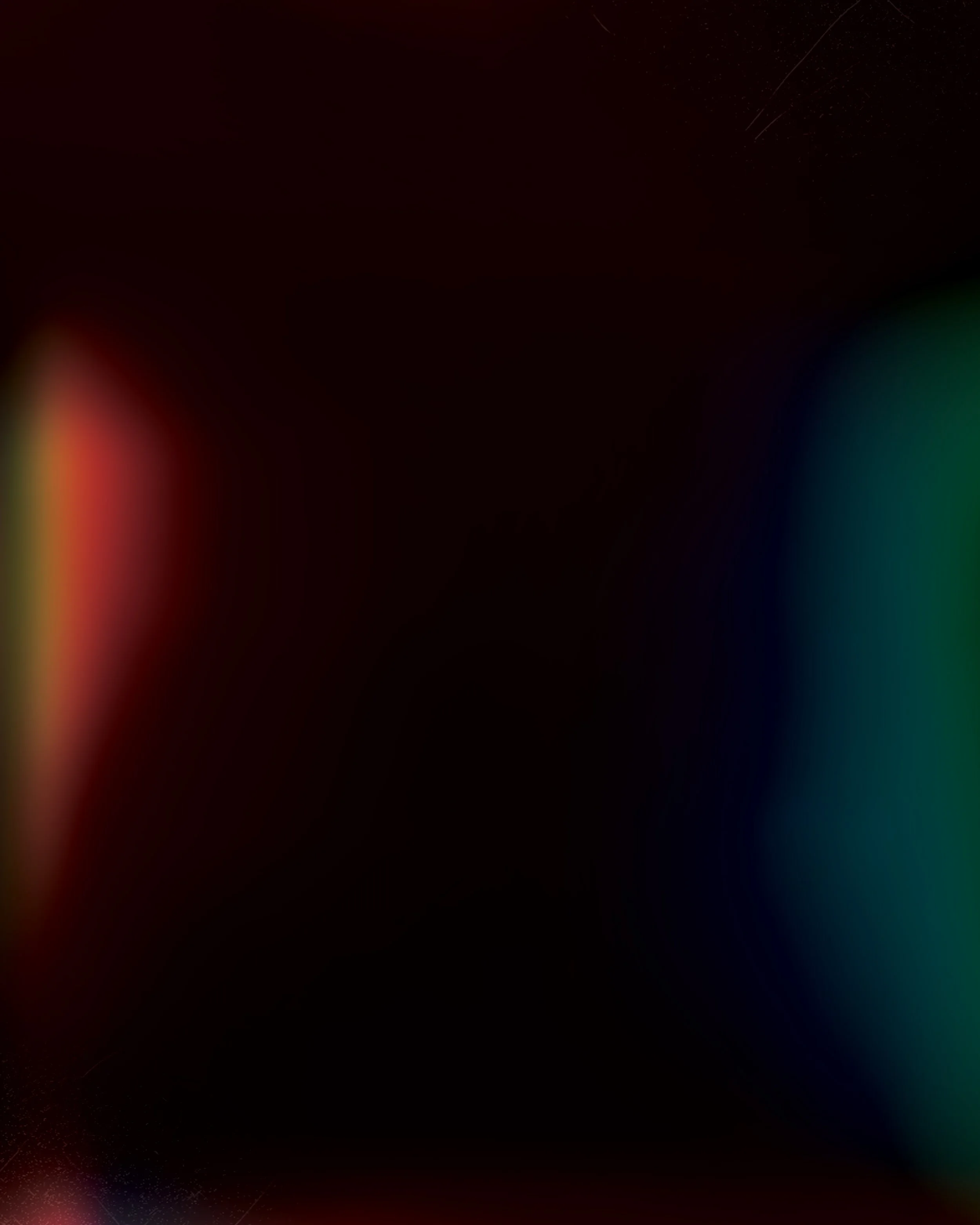 Blurred dark image with faint streaks of red, green, and blue light, and tiny white stars or sparkles visible in the upper right corner.
