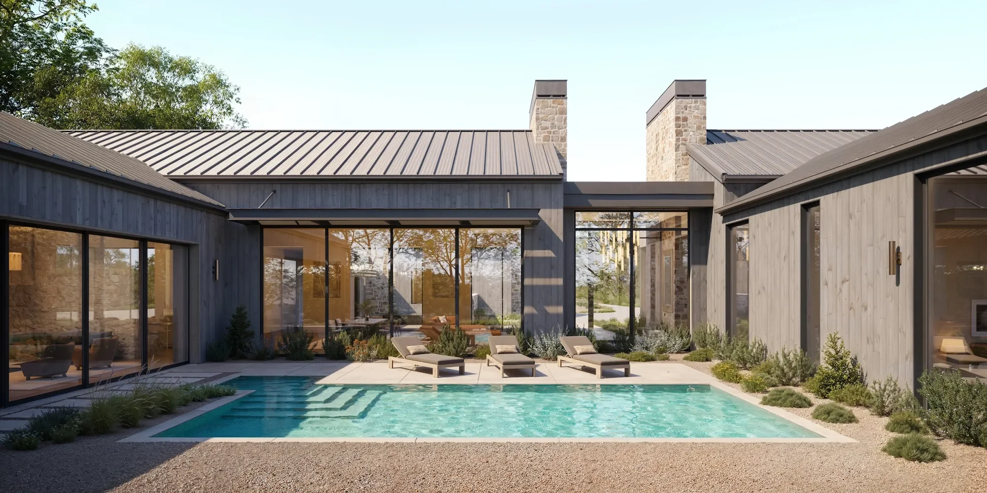 Modern house with glass walls around a backyard swimming pool, lounge chairs, and patio furniture, surrounded by landscaped plants and trees.