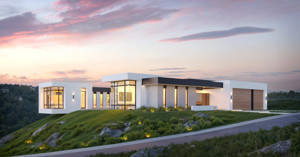 Modern house with large glass windows on a hillside at sunset, with landscaped yard and driveway.