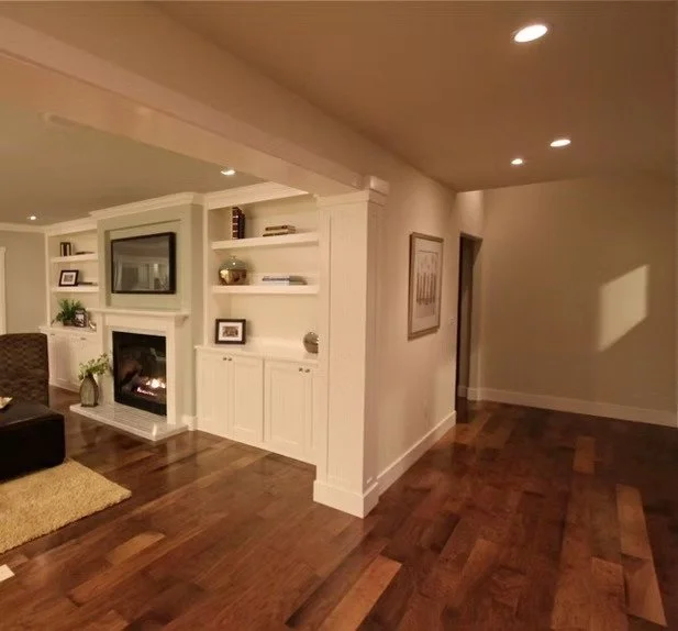 Living room with built-in white shelving, a fireplace, and hardwood floors.