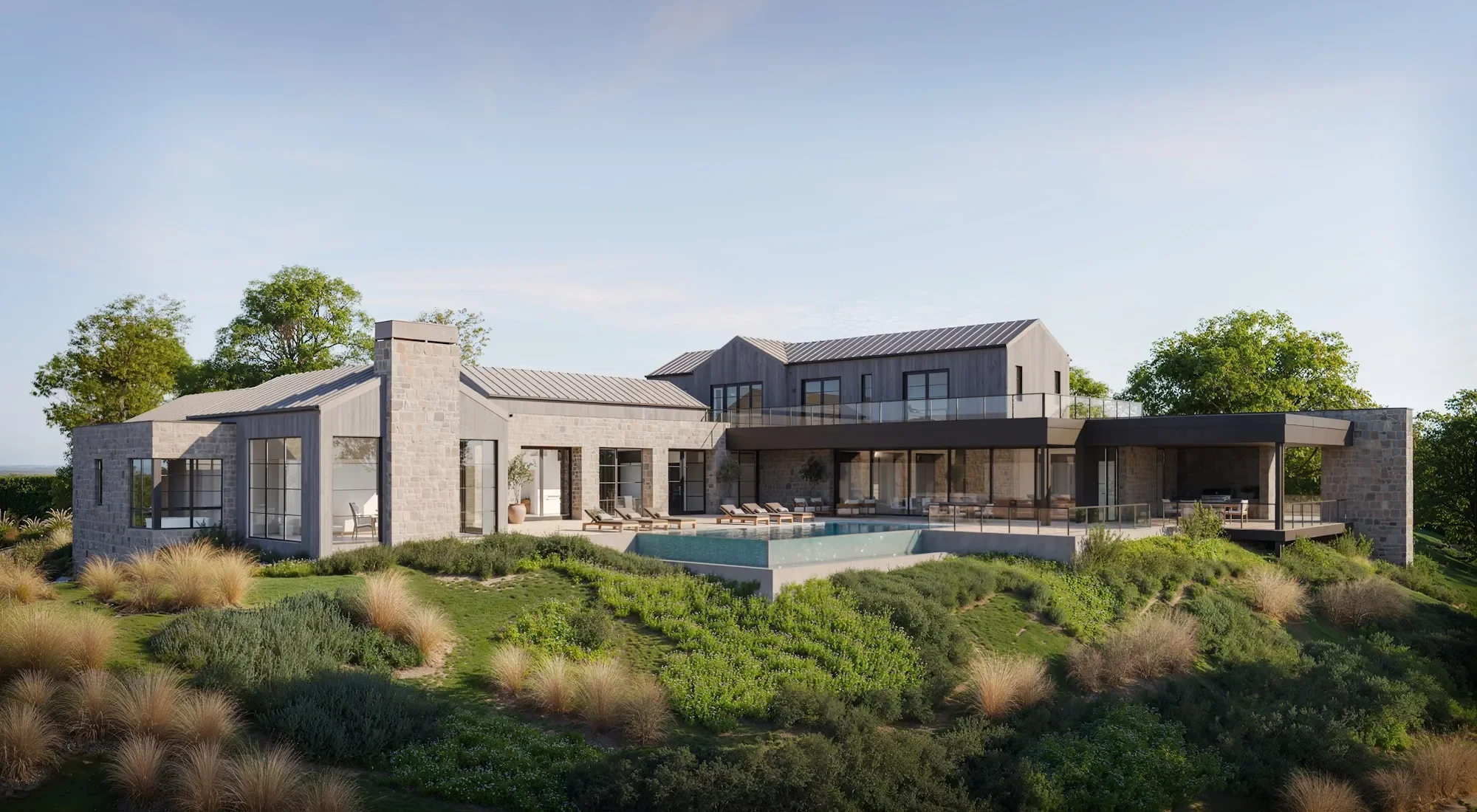 Modern two-story house with stone and wood exterior, large windows, covered patio, swimming pool, and landscaped garden, surrounded by trees under a clear sky.