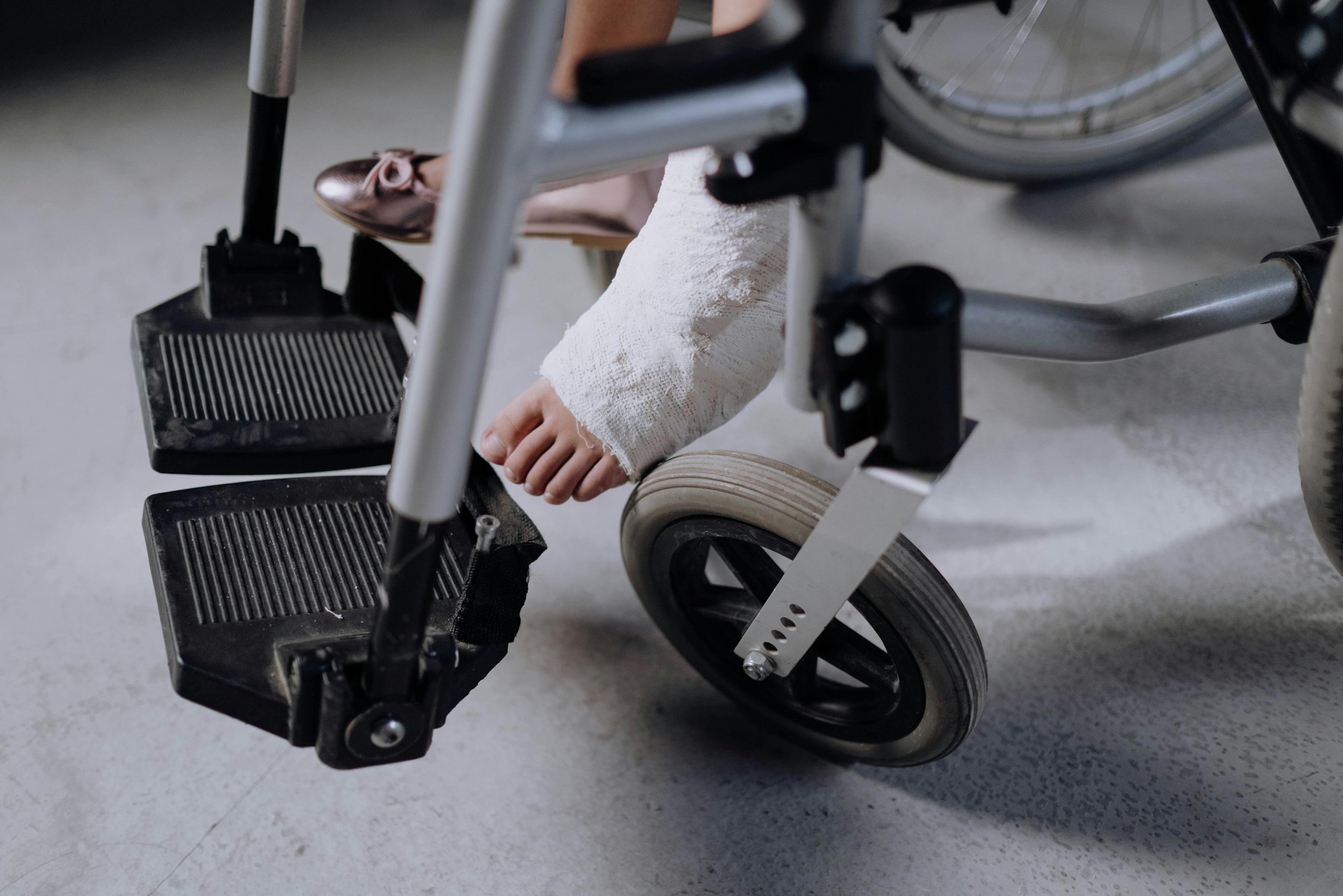 Close-up of a person's foot in a white bandage, resting on the footrest of a wheelchair.