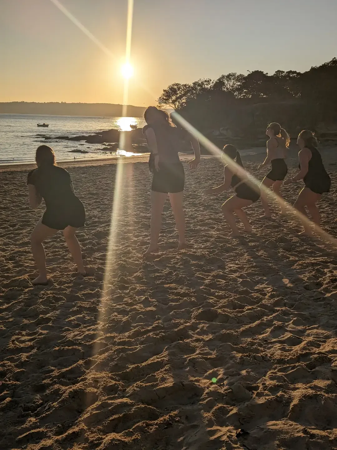 group performing squats at sunrise at the beach