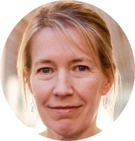 Et close-up af en kvinde med blond hår og øreringe, smilende mod kameraet.