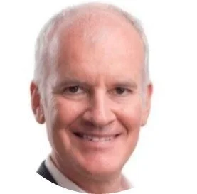 Et portræt af en mand med lys hud, gråt hår og et smil, iført en sort jakkesæt.