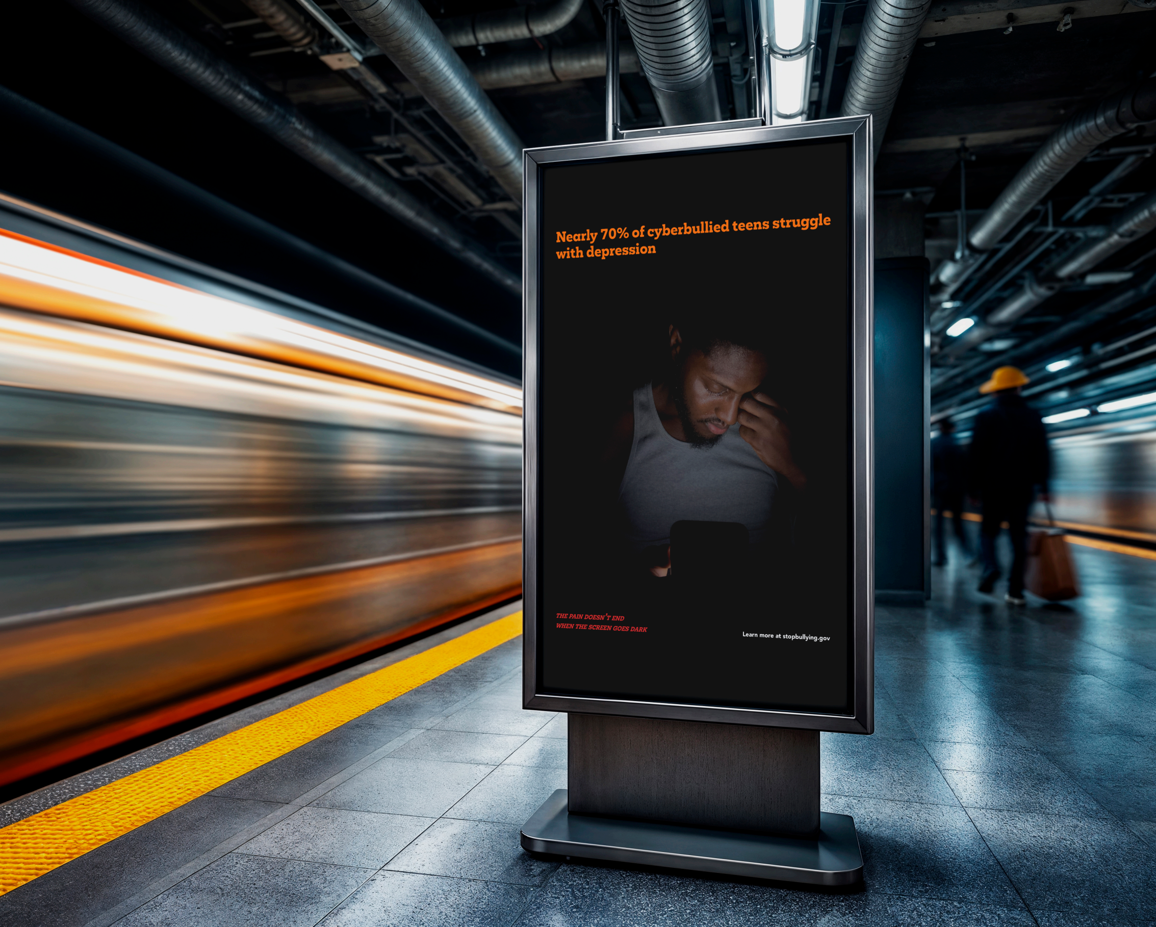 Digital billboard in a subway station displaying a message about teen depression and cyberbullying, with a blurred moving train and a person in a yellow hat in the background.