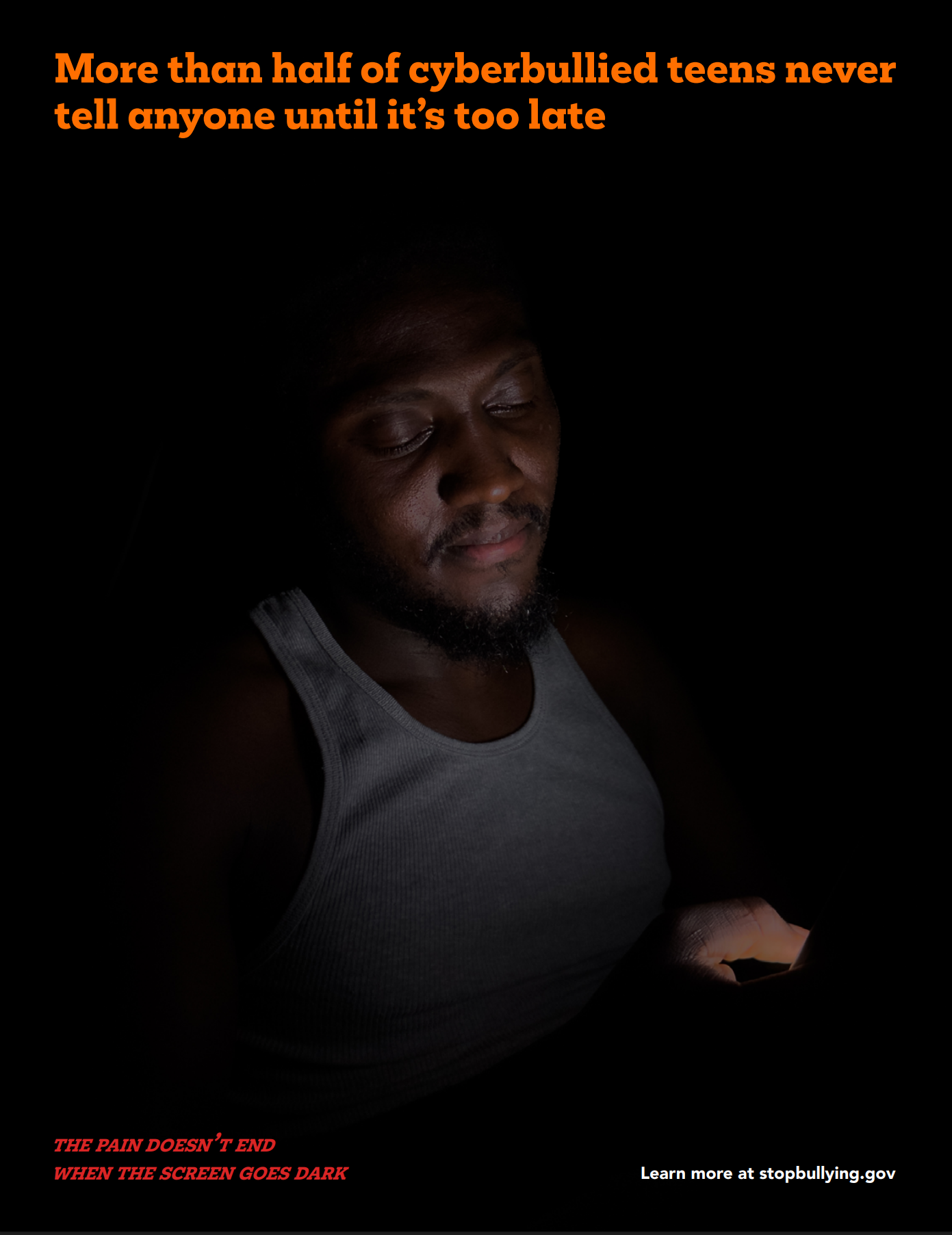 A man wearing a gray tank top looking at a smartphone in dark lighting. Orange text at the top reads, "More than half of cyberbullied teens never tell anyone until it's too late." Red text at the bottom left says, "THE PAIN DOESN'T END WHEN THE SCREEN GOES DARK." White text at the bottom right says, "Learn more at stopbullying.gov."