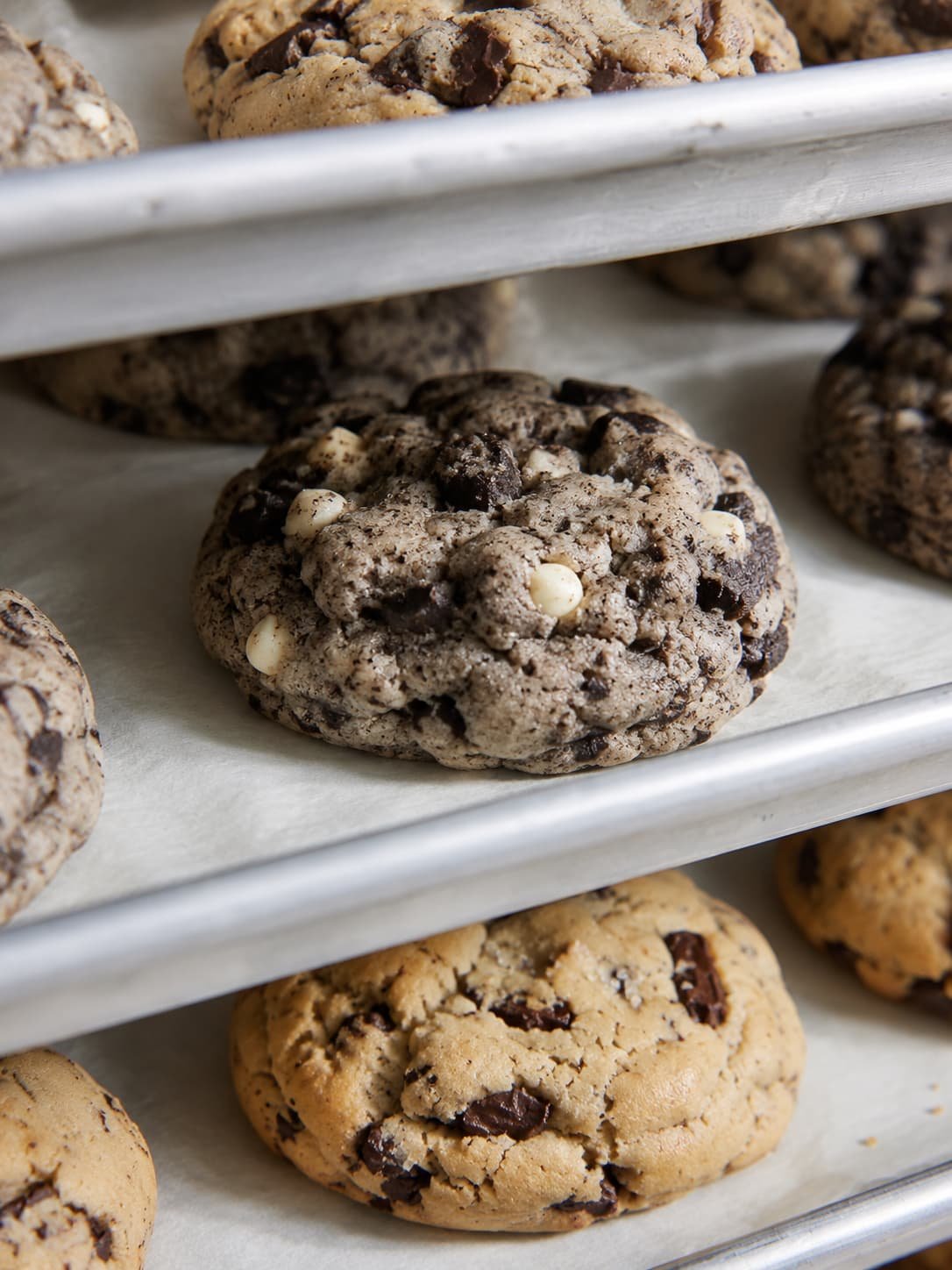 Close-up of chocolate chip cookies on baking racks, with a variety of cookies featuring white and dark chocolate chips.