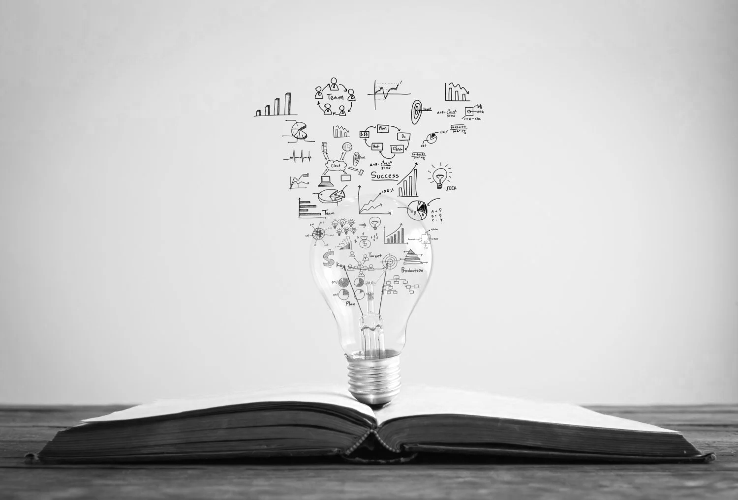Open book with a light bulb above it, filled with various sketches and diagrams related to business, strategy, and ideas.
