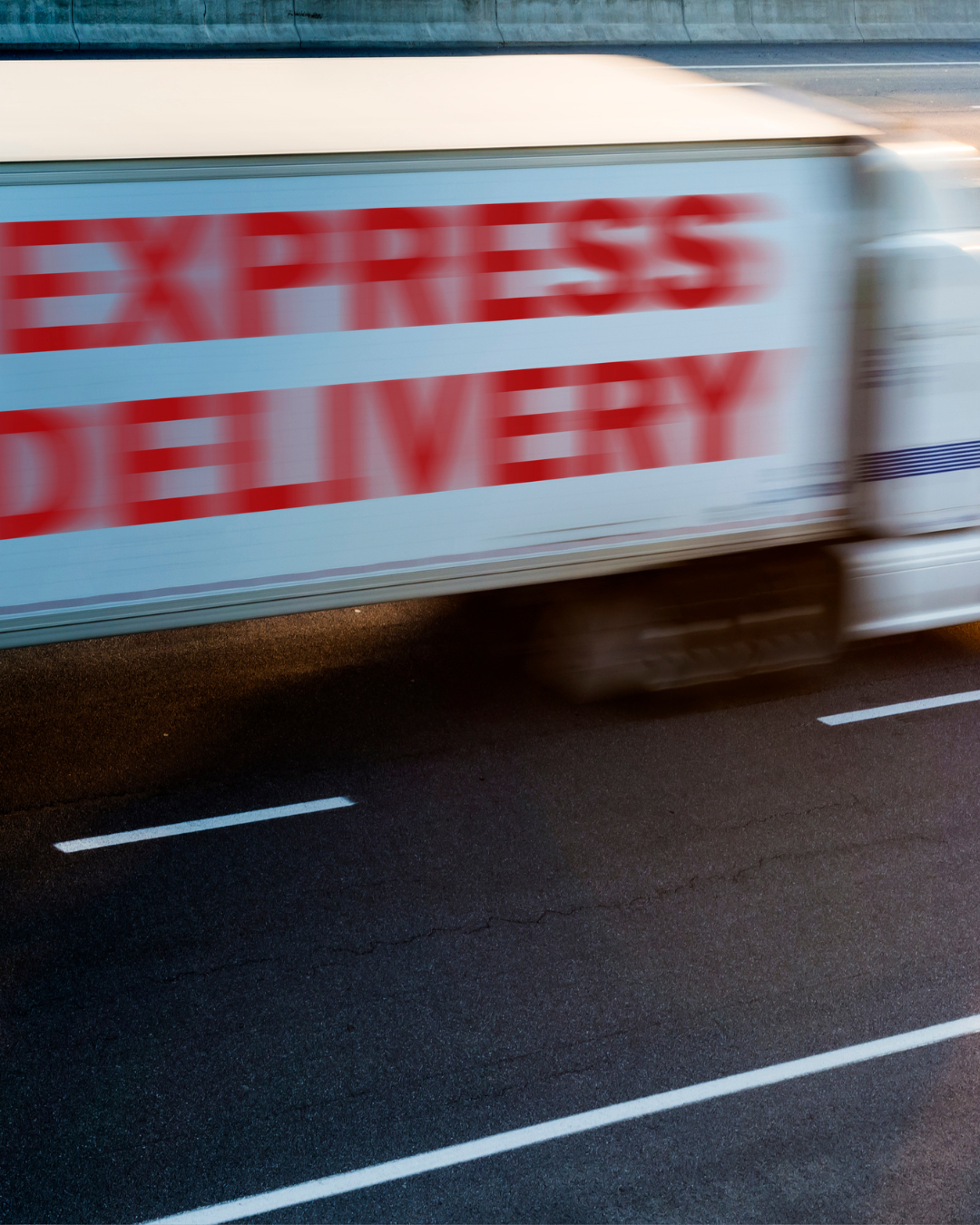 En närbild av en lastbil eller en vagn som har texten 'Express Delivery' i stora röda bokstäver, och texten är suddig på grund av rörelse.