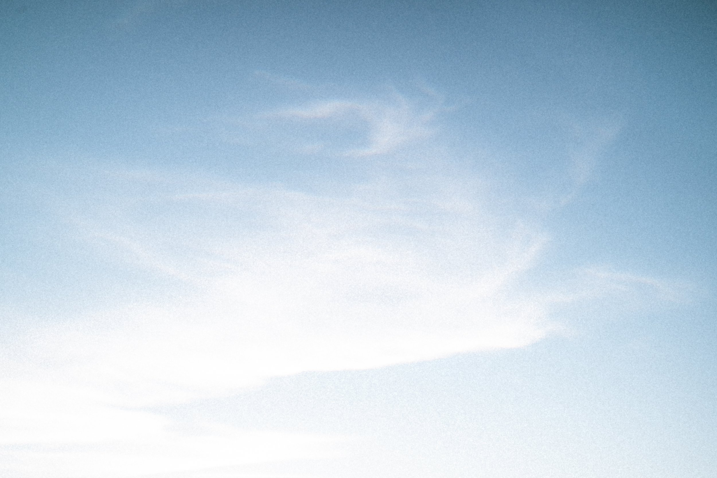 De foto toont een heldere blauwe hemel met enkele lichte, dunne wolken.