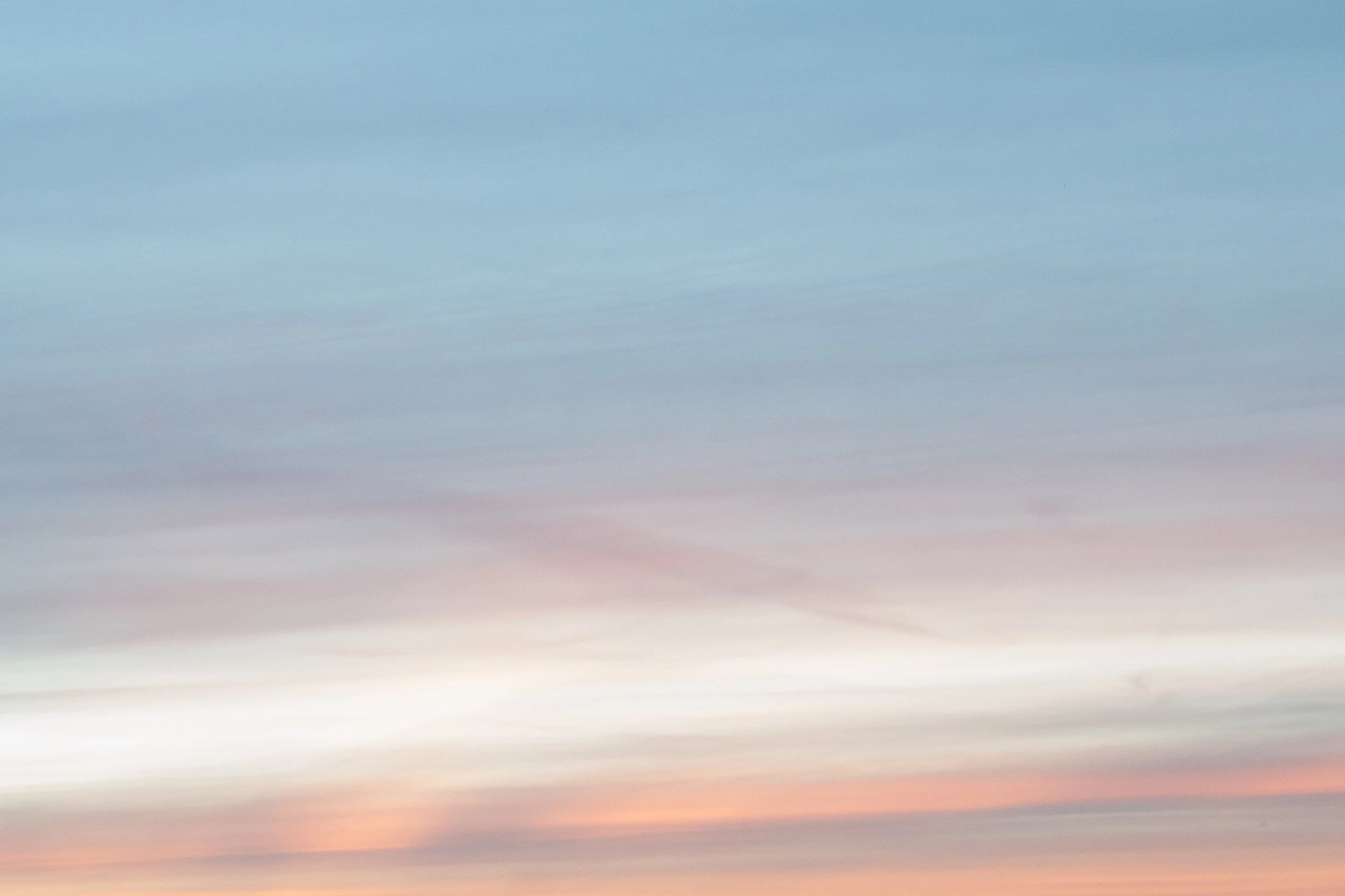Een pastelgekleurde hemel met zachte wolken en een roze-achtige tint in de lucht.