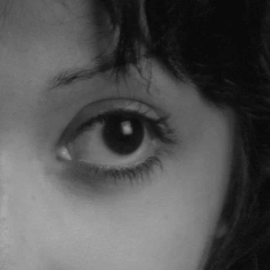 Close-up of a person's eye and part of their face with curly hair.