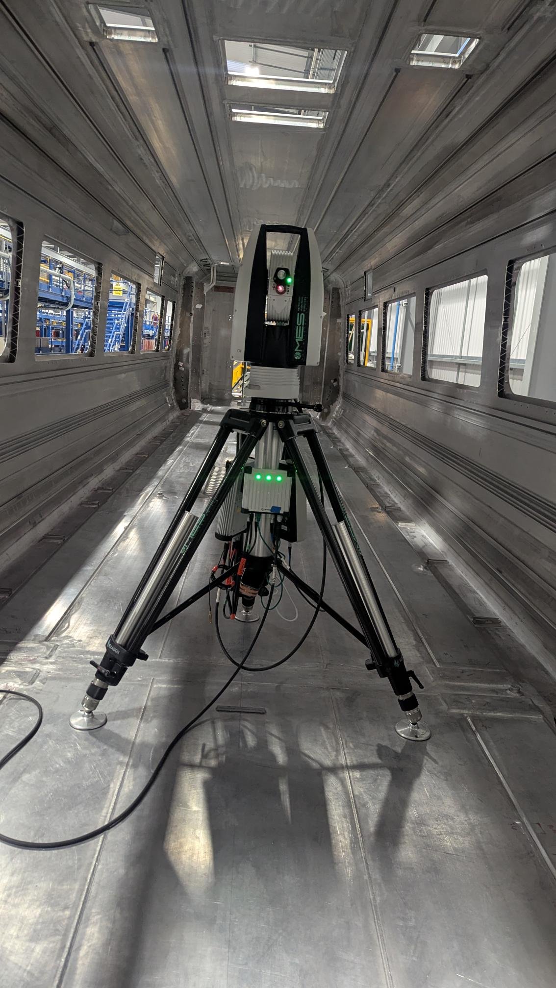 A robotic device with lights, situated on a metallic surface in an industrial or laboratory environment.