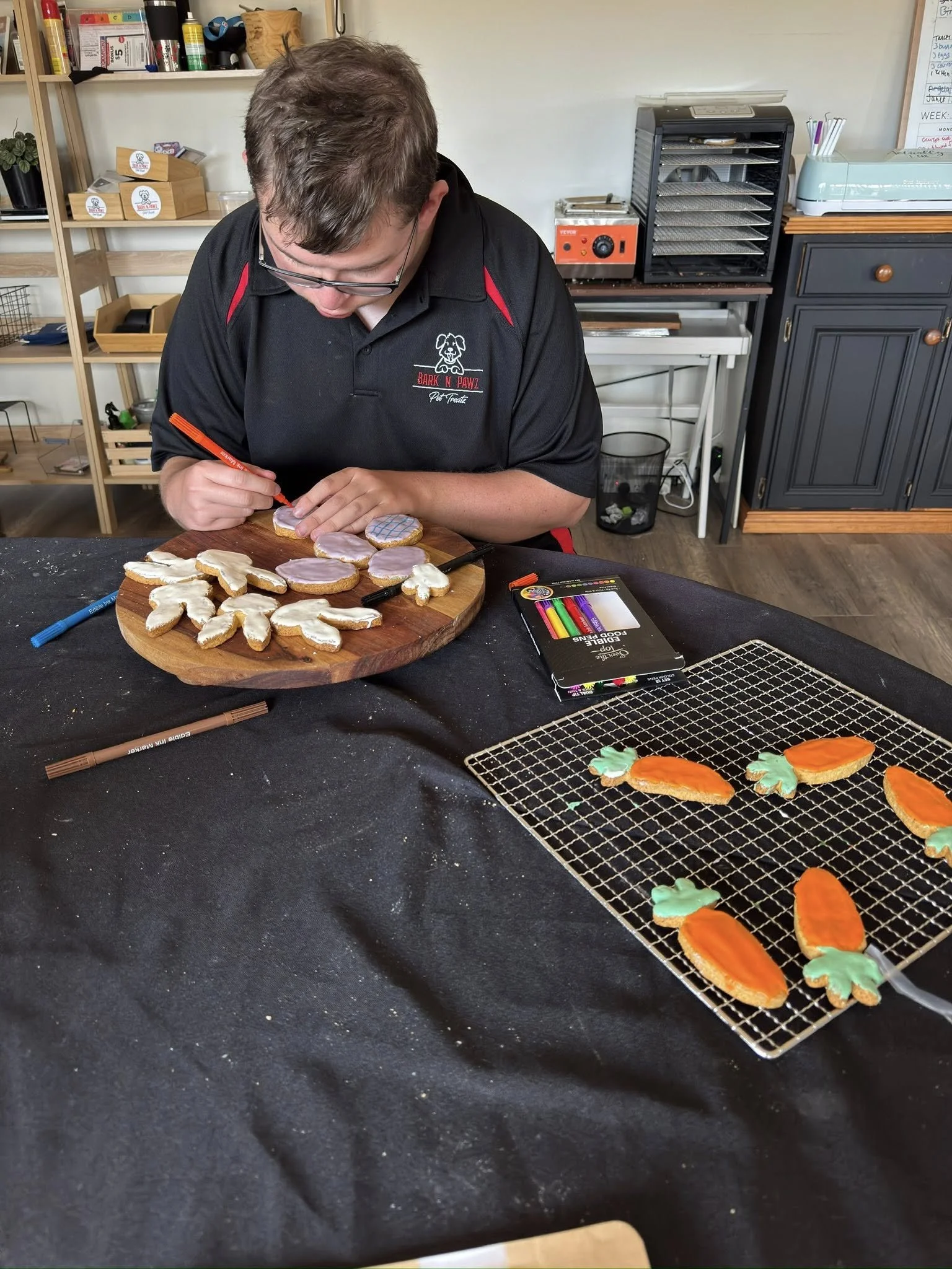Man decorating Halloween dog cookies with icing and decorated cookies.